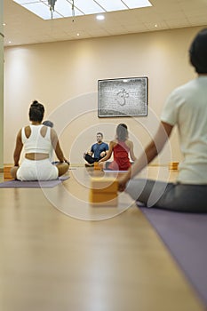 yoga teacher teaching a class in Sukhasana pose