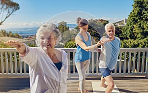 Yoga is their secret to staying young. a senior couple doing yoga together with an instructor on their patio outside.