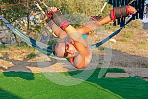Yoga treatment for core, yoga swing, slim young man strapped to four planks above the ground, man developing endurance