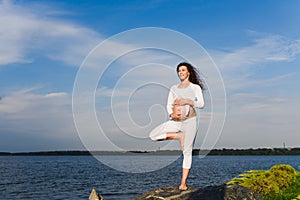 Yoga tree pose by pregnat woman.