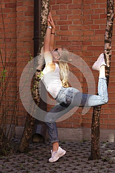 Yoga between two trees. Sexy blonde demonstrates a pose with her legs crossed on a tree