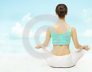 Yoga woman back view meditate sitting in lotus pose over sky background.