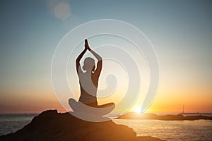 The yoga woman meditating in the lotus position on the beach during a beautiful sunset.