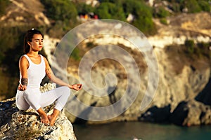 Yoga woman meditating at sunset or sunrise in black sea Crimea.