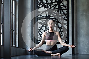 Yoga woman meditating after workout in studio / loft near window