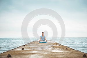 Yoga woman meditation in lotus position at pebble sea beach sunset sky horizon healthy lifestyle