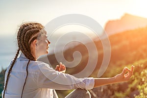 Yoga woman mountains. Profile of a woman doing yoga in the top of a cliff in the mountain. Woman meditates in yoga asana