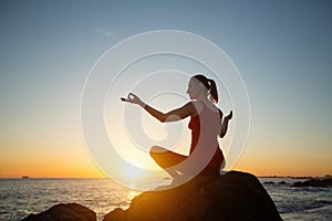 Yoga woman on the ocean coast during warm  sunset