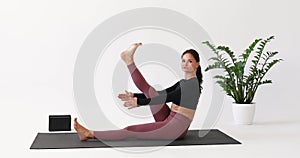 Yoga woman performs Paripurna Navasana exercise, boat pose with alternating leg lifts and foot warm-up