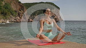 Yoga woman practices yoga and meditates in lotus position on beach sea.