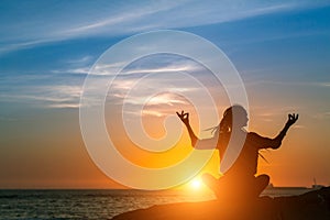 Yoga woman silhouette. Meditation on the Ocean during amazing sunset.