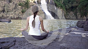 Yoga woman sit in meditation pose near waterfall in Dalat, Vietnam