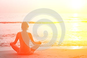 Yoga woman sitting in lotus pose on the beach during sunset