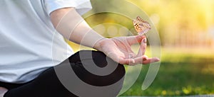 Yoga. A woman in sportswear meditates sitting on a Mat in a Park on the grass. Hand with butterfly close-up. Panorama. Concept of