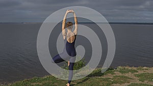 Yoga woman in sportswear pose against lake