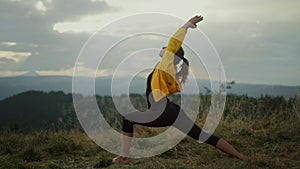 Yoga woman standing in warrior pose. Fit girl meditating in mountains