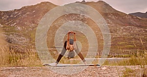 Yoga, woman and stretching outdoor for fitness, wellness and mindfulness on mountain. Sunset, zen chakra and calm female