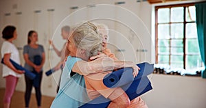 Yoga, women and friends hug at class for greeting, meeting and exercise together. Pilates, happy and senior people