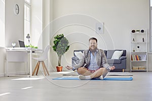 Yoga work at home. Funny fat man practices yoga meditation while sitting on the floor in the room online at home.