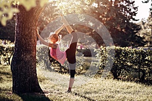 Yoga. Young woman practicing yoga or dancing or stretching in nature at park. Health lifestyle concept