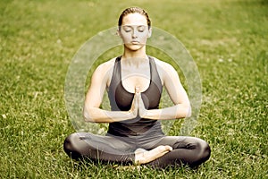 Yoga. Young woman practicing yoga meditation in nature at the park. lotus pose. Health lifestyle concept