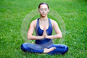 Yoga. Young woman practicing yoga meditation in nature at the park. lotus pose. Health lifestyle concept