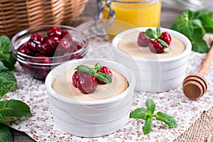 Yoghurt with fresh juicy cherries on a wooden table