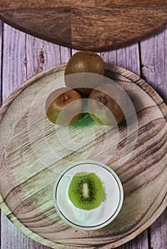 Yoghurt glass on wooden plate with kiwis photo