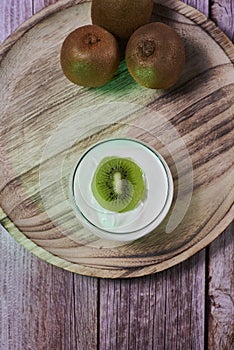 Yoghurt glass on wooden plate with kiwis photo