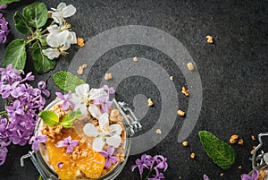 Yoghurt with granola, orange, mint and edible flowers