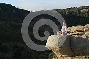 Yogi doing yoga and meditating in the top of a cliff