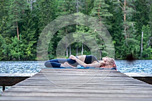 Yogi  girl  practicing yoga, Reclining Hero exercise, Virasana pose on the lake. The concept of appeasement,  healthy