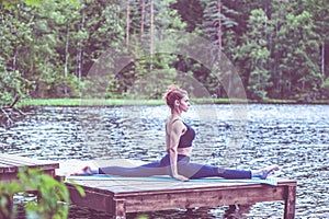 Yogi  girl  practicing yoga, stretching in Monkey God exercise, Splits, Hanumanasana pose on the lake. The concept of
