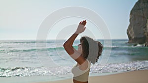 Yogi girl standing sand near ocean waves making Namaste hands. Woman meditating.
