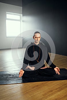 The yogi man do pranayama in the lotus position with gyan mudra. Yoga practice in the studio.