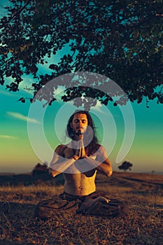 Yogi man meditating at sunset on the hills. Lifestyle relaxation emotional concept spirituality harmony with nature