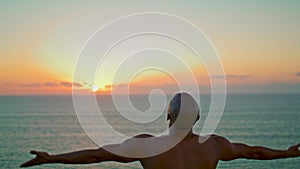 Yogi silhouette practicing asana in beautiful sunset. Strong man relaxing alone