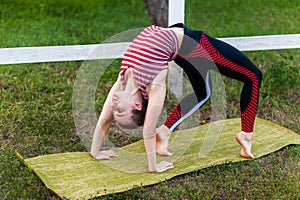 Yogi woman practicing yoga, stretching in wheel exercise, urdhva dhanurasana pose working out on mat