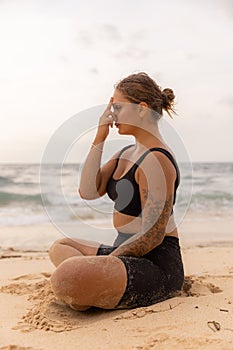 Yogi woman sitting in lotus pose, practicing Anuloma Viloma Pranayama, Alternate Nostril Breathing. Control prana, control of