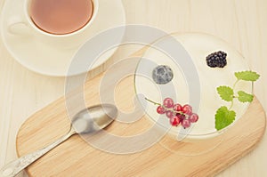 Yogurt with berries in glass on a wooden tray and a cup of tea/yogurt with berries in glass on a wooden tray and a cup of tea. Top