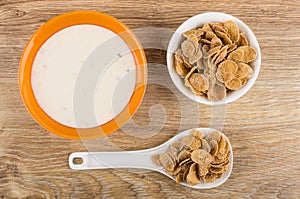 Yogurt in bowl, flakes in bowl, in spoon on table