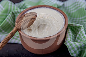 Yogurt in a brown ceramic bowl on a wooden table. Homemade yogurt or sour cream in a rustic bowl