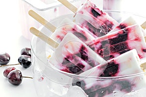 Yogurt and cherries popsicles in a bowl.