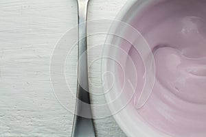 Yogurt close up view form top - Natural rasberry flavored yoghurt in white bowl on wood table