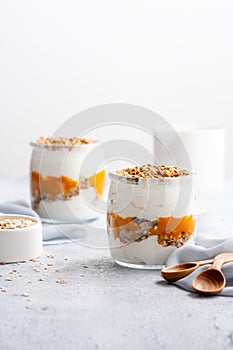 Yogurt cream with sea buckthorn sauce and granola in a glass jar on a bright morning table. The concept of a healthy