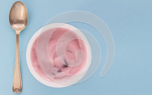 Yogurt cup with pink strawberry yoghurt isolated on baby blue background with copy space - selective focus image photo