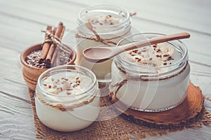Yogurt in glass jars on wooden background