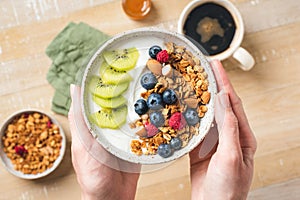 Yogurt and granola bowl with berries in female hands