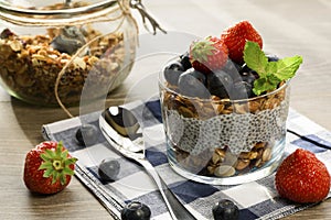 Yogurt with granola, fresh blueberries, chia seeds and oats in a glass over wood background. close up