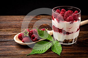 Yogurt with granola, raspberry and raspberry jam on dark wooden background